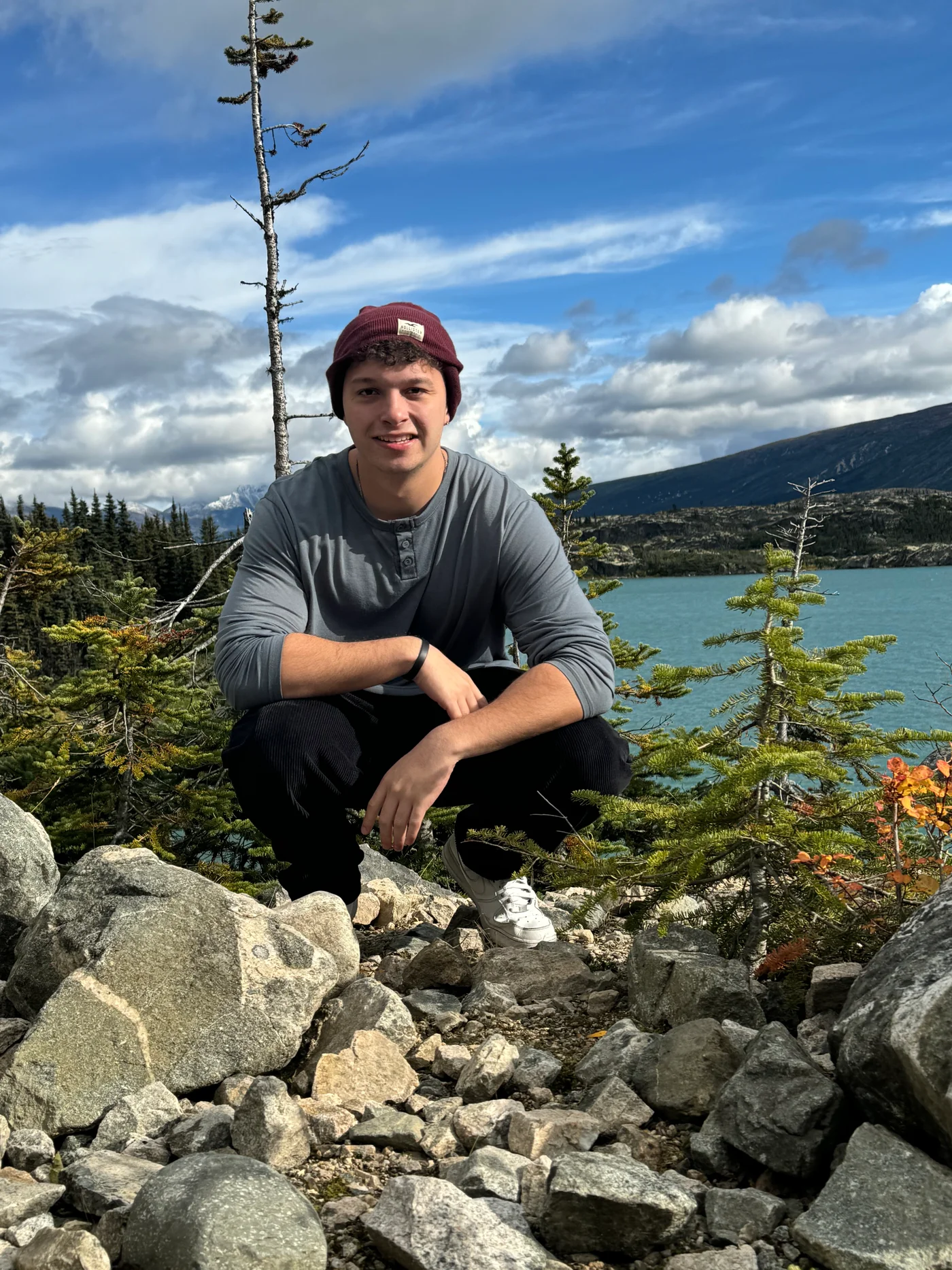 Alex smiling outdoors beside a mountain lake